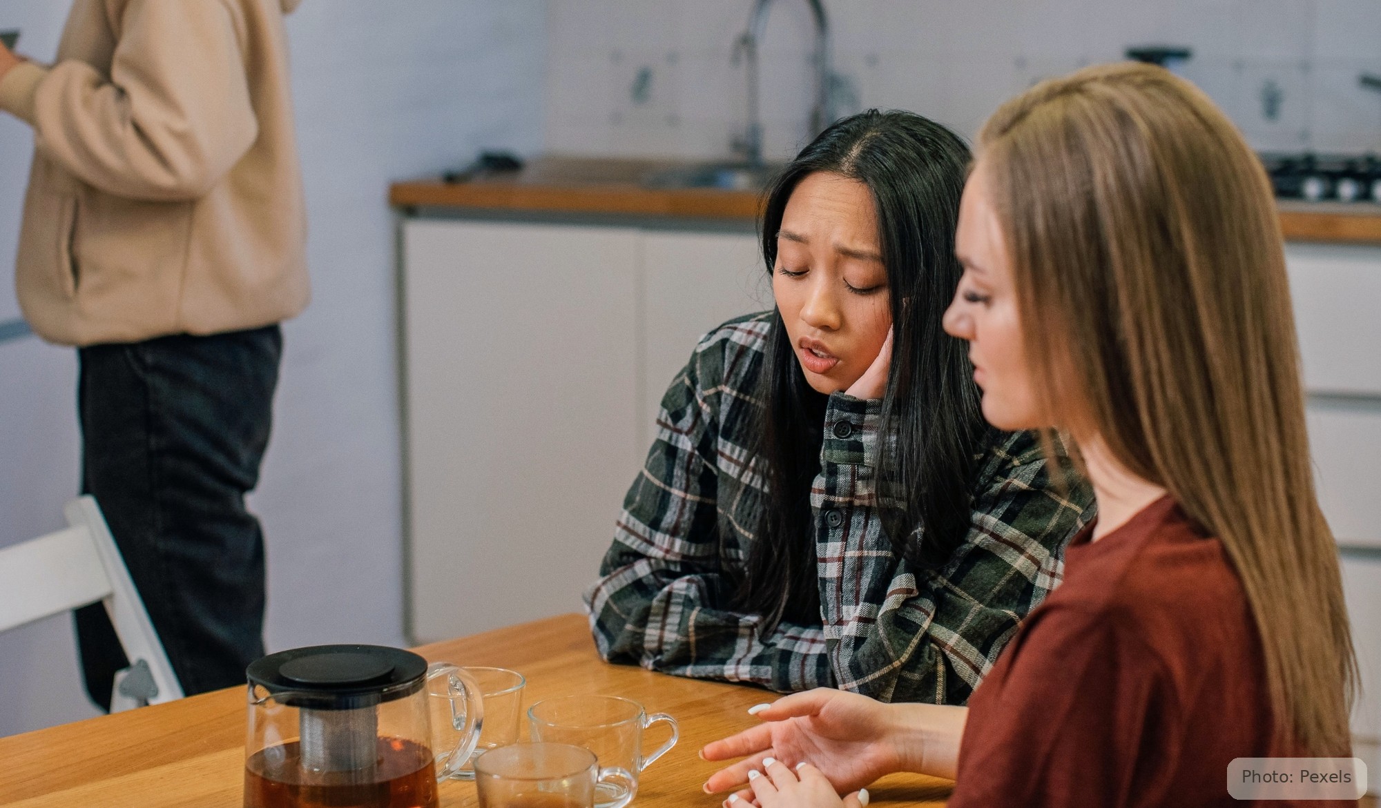 A woman talks with a caring listener across a table, unhurried and safe.