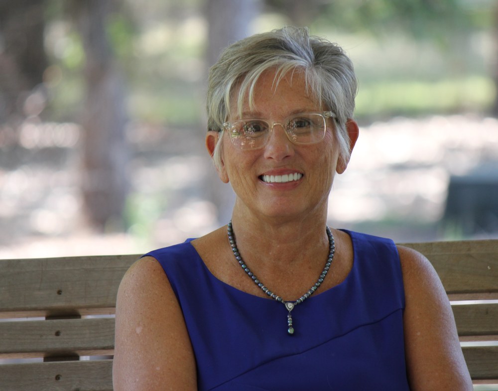 Sharon King, founder of Mercy Manor, seated on a bench outdoors.